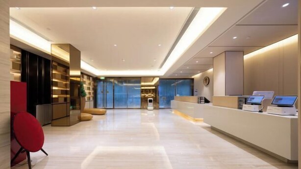 A modern reception area with a clean, minimalist design, featuring a reception desk, seating area, and a view into the building. - JI Hotel (Beijing South Railway Station Jiaomen East Subway Station) (Beijing)