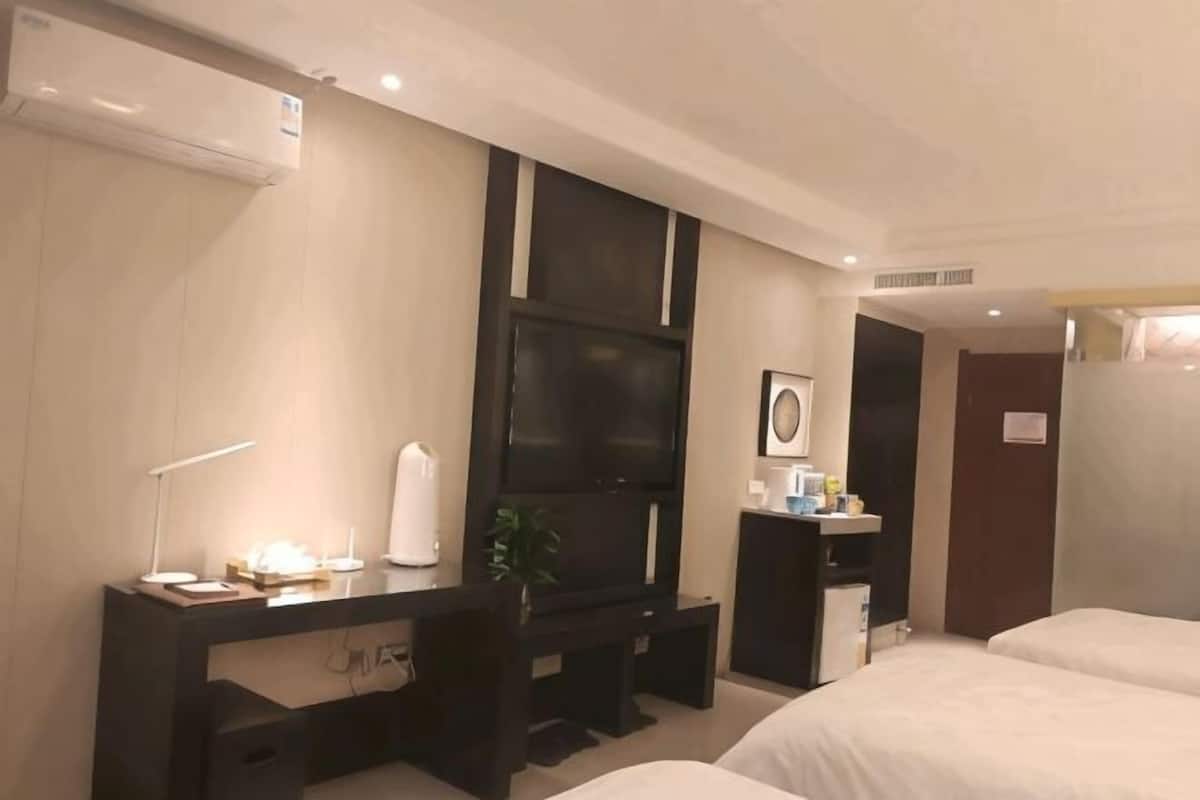 A hotel room with a bed, a desk with a computer, a TV, and a small bathroom.