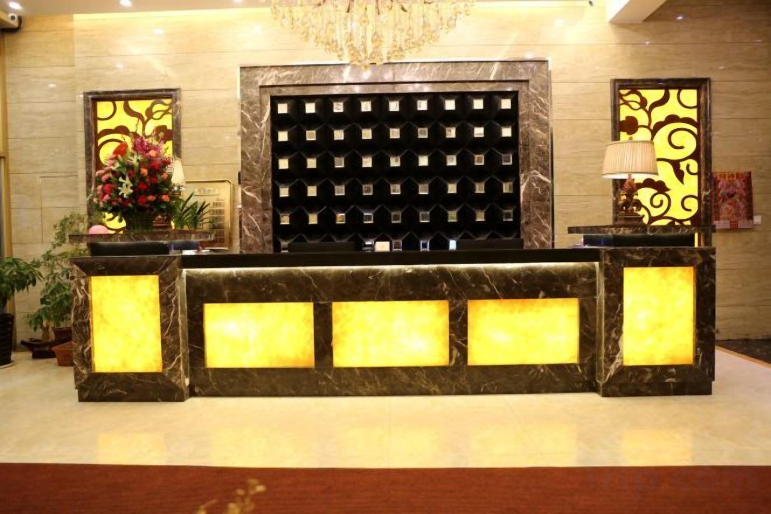 A reception desk with a marble top, a black decorative panel, and a chandelier above.