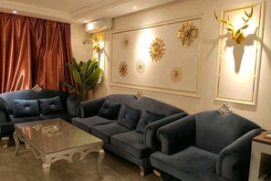 Un salon comprenant un ensemble de canapés, une table basse en verre et des œuvres d’art décoratives accrochées au mur.