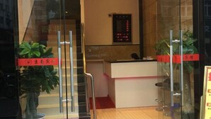 Een receptiezone met een glazen scheiding, een receptiebalie en een digitaal displaybord.