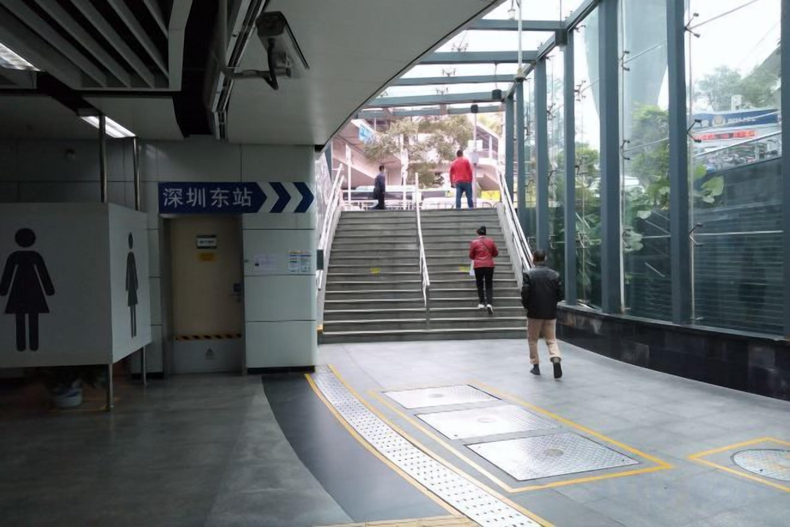 A subway station with stairs leading to an exit, a directional sign, and a glass wall.