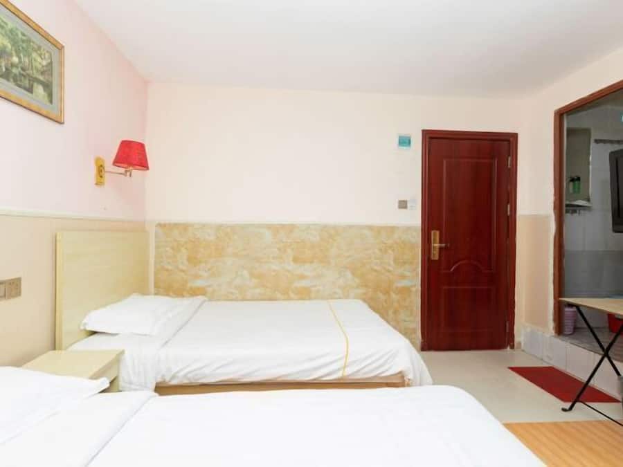 Una habitación de hotel con dos camas, un televisor, una lámpara roja y una puerta de madera.