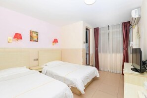 Habitación de hotel con dos camas, un escritorio, un televisor y una ventana con cortinas.