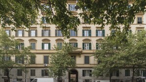 A multi-story building with a symmetrical facade, large windows with shutters, and an entrance with a decorative archway. - Elegant Apartment in the Heart of Prati with Comfortable Rooms (Roma)