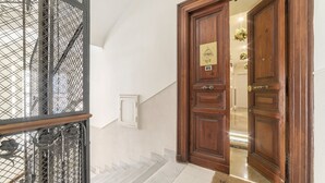 A hallway with a wooden door, a metal gate, and a staircase. - Elegant Apartment in the Heart of Prati with Comfortable Rooms (Roma)