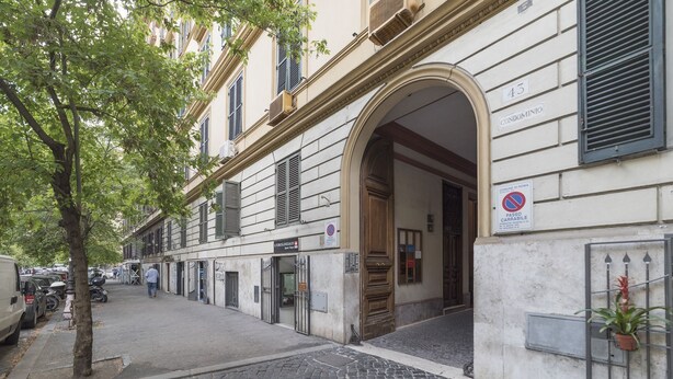 A building with a large arched entrance, a sign indicating a no parking zone, and a sign for a medical facility. - Elegant Apartment in the Heart of Prati with Comfortable Rooms (Roma)