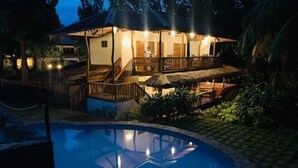 Ein zweistöckiges Gebäude mit Balkon und einem Pool im Vordergrund.