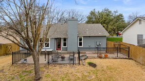 A residential house with a fenced backyard, a patio with outdoor furniture, and a chimney. - Austin Cozy 2BR — Yard, Fire Pit, Pet OK, Sleeps 6 (Austin)