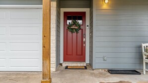 A red door with a welcome wreath, a mailbox, and a stone pillar. - Austin Cozy 2BR — Yard, Fire Pit, Pet OK, Sleeps 6 (Austin)
