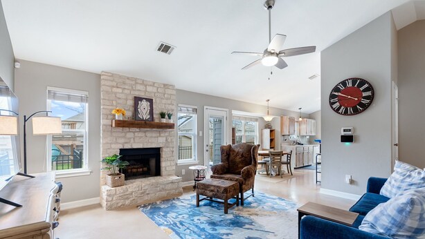 A spacious living room with a fireplace, a blue patterned rug, a blue sofa, and a dining area in the background. - Austin Cozy 2BR — Yard, Fire Pit, Pet OK, Sleeps 6 (Austin)