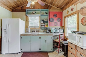 A compact kitchen with a refrigerator, microwave, and wooden cabinets.