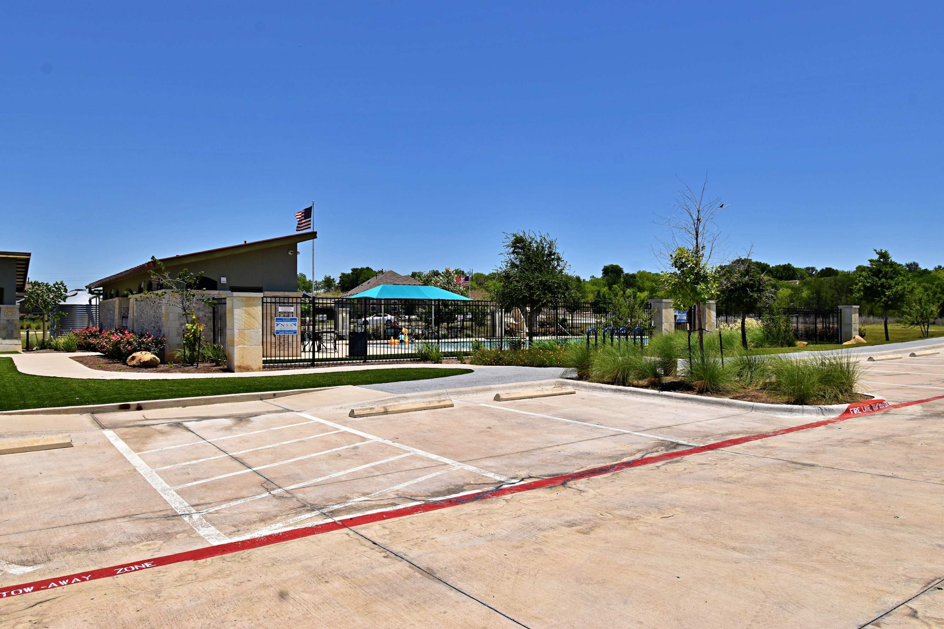 A parking lot with marked spaces, a tow-away zone, and a building with a blue roof.