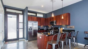 A modern kitchen with dark wood cabinets, stainless steel appliances, and a central island with bar stools.