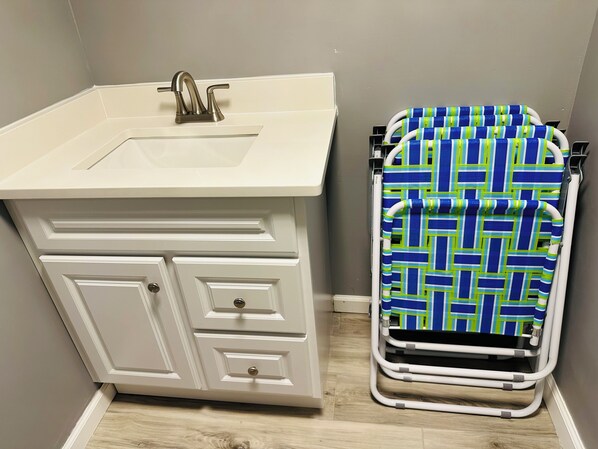 A bathroom with a sink, vanity, and a wheelchair-accessible shower chair.