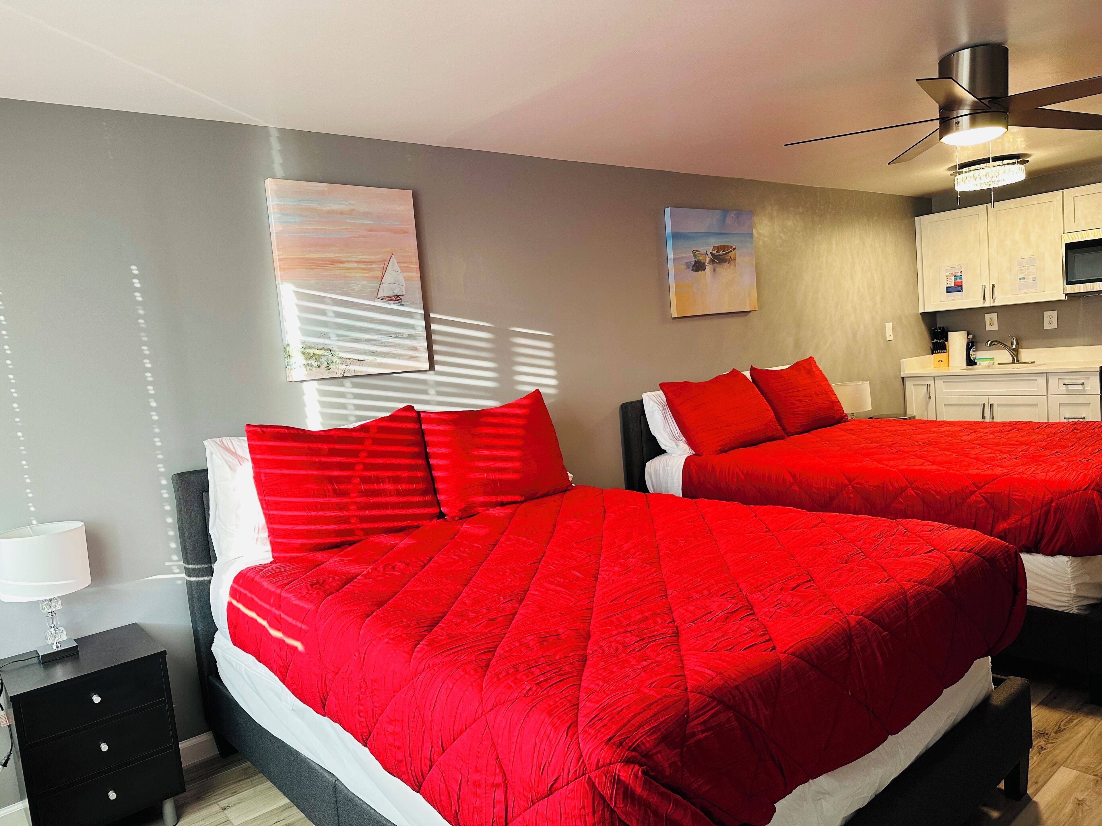 Een hotelkamer met twee bedden, een kitchenette en kunst aan de wanden.