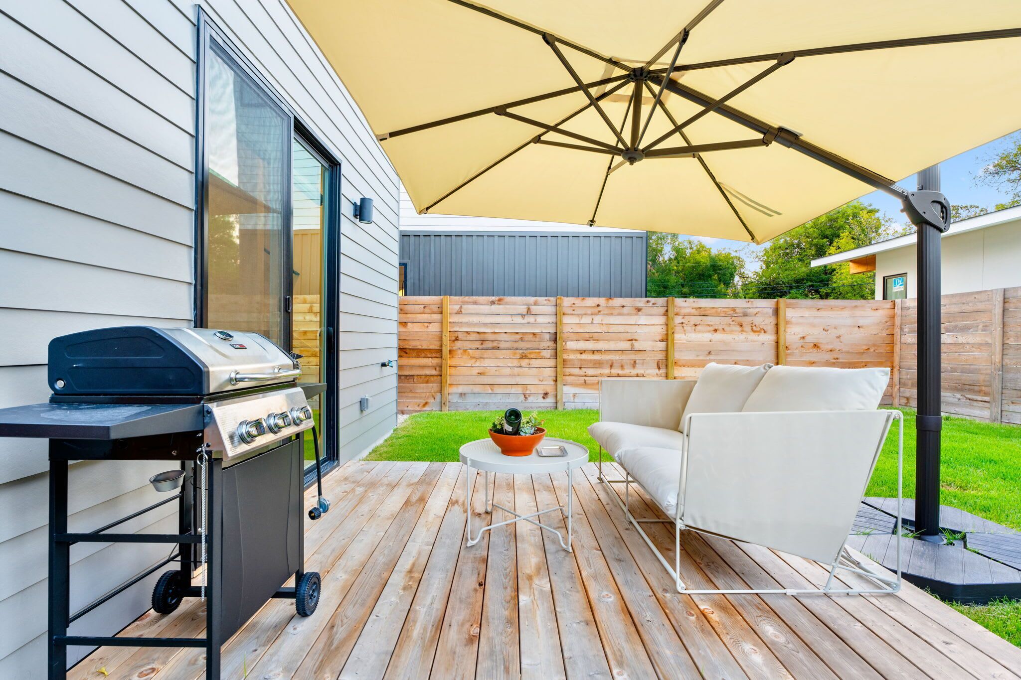 A patio with a grill, outdoor furniture, and a large umbrella.