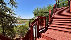 A wooden staircase leading to a viewing platform with a clear view of a lake and surrounding greenery. - Lakefront Escape | PingPong + Fire Pit | Sleeps 12 (Spicewood)