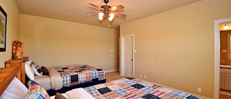 A bedroom with two beds, a ceiling fan, a door, and a small table with a statue.