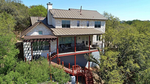 A two-story stone house with a covered porch and a red staircase. - Lakefront Escape | PingPong + Fire Pit | Sleeps 12 (Spicewood)