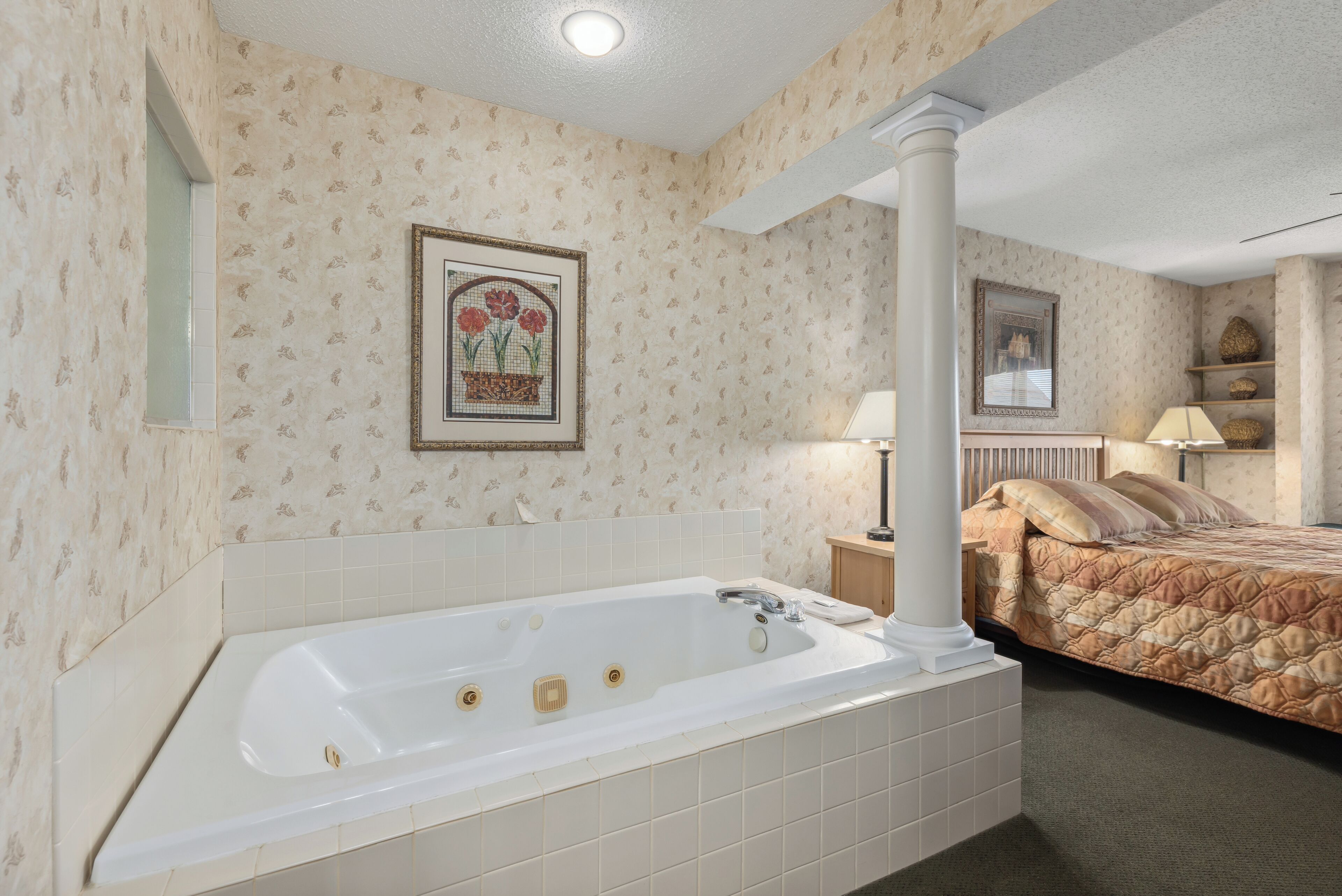 A bathroom with a large bathtub, a mirror, and a framed picture on the wall.