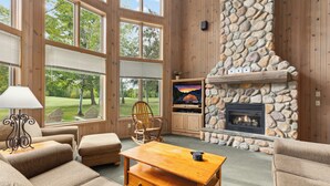 Una sala de estar acogedora con chimenea de piedra, ventanas amplias y asientos cómodos.