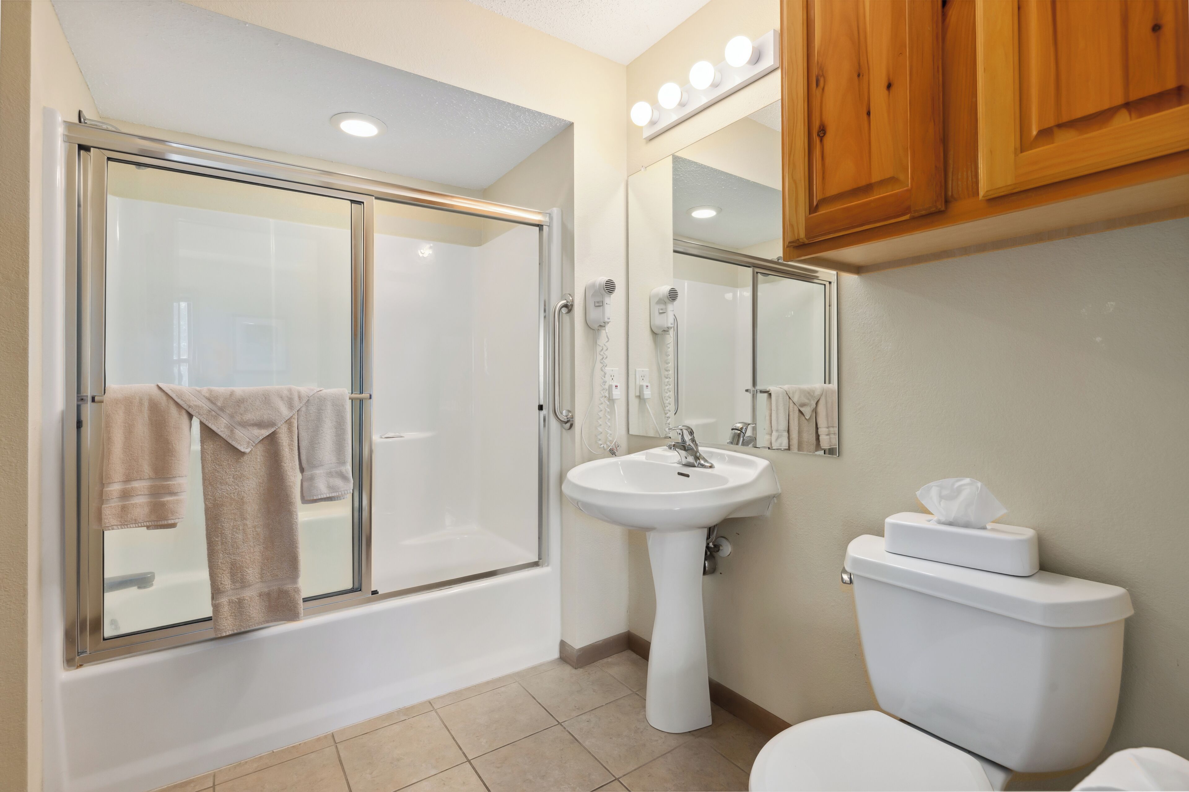 A bathroom with a glass-enclosed shower, a pedestal sink, and a toilet.