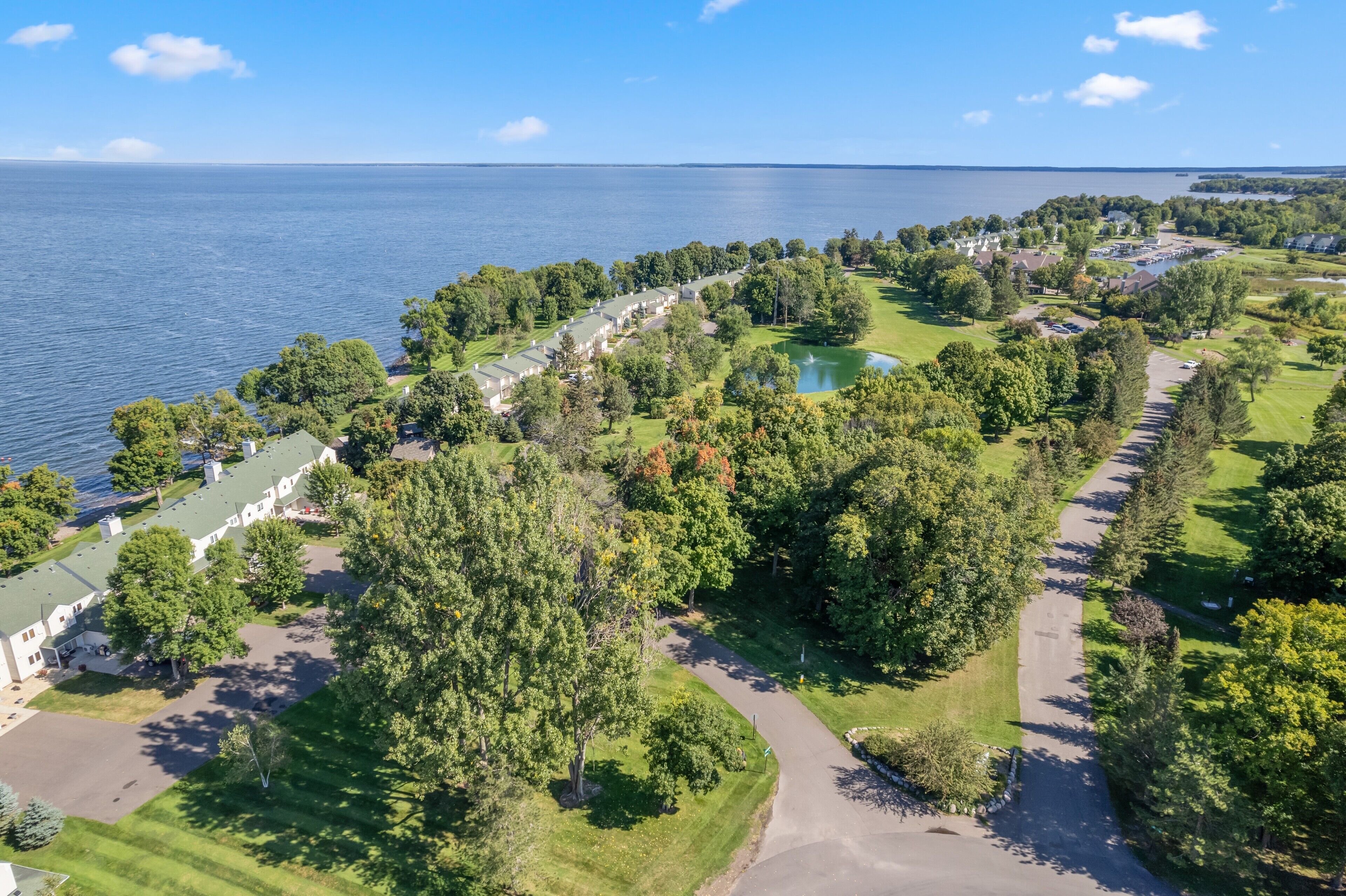 An aerial view of a coastal resort with multiple buildings, a golf course, and a lake.