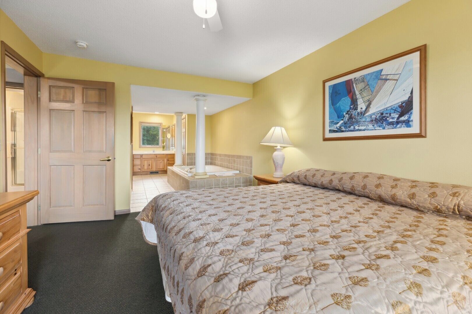 Une chambre d’hôtel avec un lit, une salle de bain avec une baignoire et un tableau au mur.