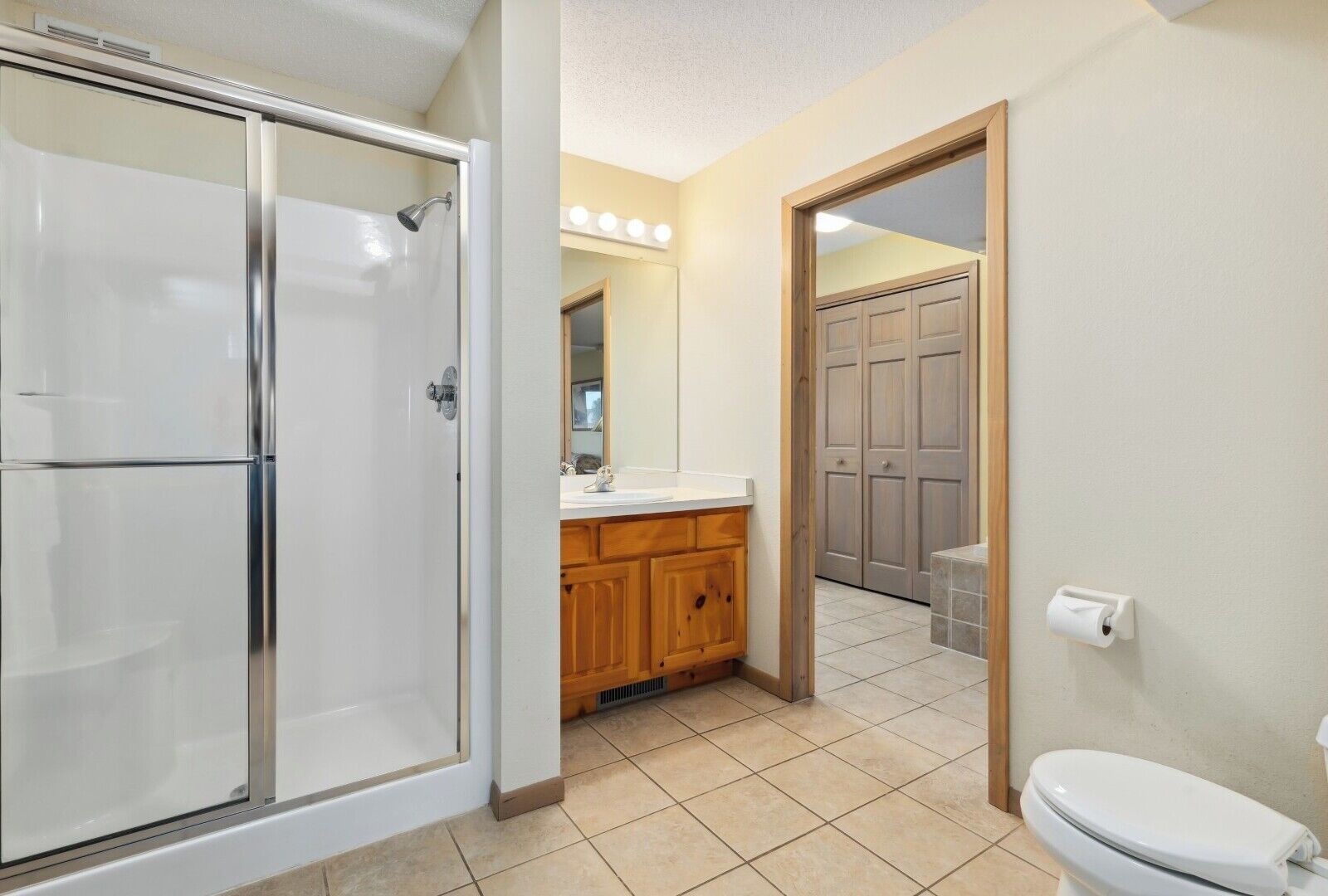 Une salle de bain avec une douche à parois de verre, un meuble-lavabo en bois, des toilettes et un miroir.