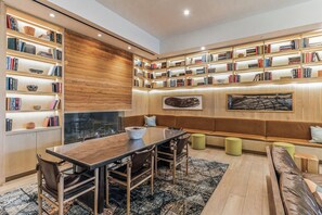 Un salon moderne comprenant un coin repas, des étagères en bois, une cheminée et un grand tableau abstrait.