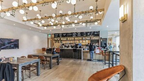 Een modern café met houten tafels, hangende bolvormige lampen en een bar.