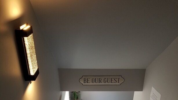 A staircase with a sign that reads "BE OUR GUEST" and a small sign with text below it.