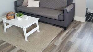 A modern living room with a grey sofa, a white coffee table, and a framed picture on the wall.