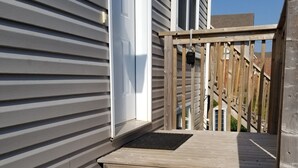 A wooden staircase leading to a deck area with a wooden fence and a door.