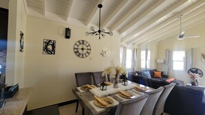 Een eetruimte met een tafel voor vier personen, een kroonluchter en een bank op de achtergrond.