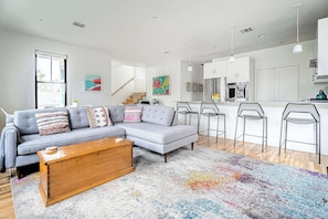 A modern living room with a grey sectional sofa, a wooden coffee table, and a colorful rug. - Rooftop Deck | 2 Miles to Downtown (Austin)