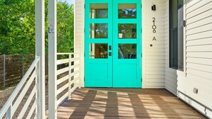 A turquoise double door with a white porch and a wooden deck. - 3BR w/ Rooftop Deck, Near DT, Sleeps 6! (Austin)