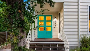 A house with a green door, white exterior, and a staircase leading to the entrance. - 3BR w/ Rooftop Deck, Near DT, Sleeps 6! (Austin)