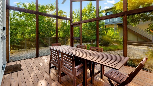 A wooden deck with a table and chairs, large windows, and a ceiling fan. - 3BR w/ Rooftop Deck, Near DT, Sleeps 6! (Austin)