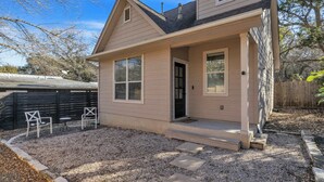A single-story house with a front porch, a small attached garage, and a gravel driveway. - South Austin 2BR | Close to SoCo/Zilker | Sleeps 4 (Austin)