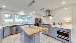 Una cocina moderna con una isla central, electrodomésticos de acero inoxidable y un amplio ventanal.