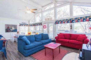 Una sala de estar con un sofá azul, un sofá rojo y un mueble para televisión.