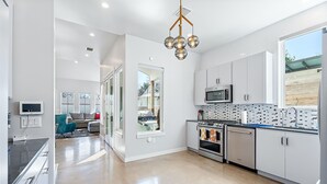 Uma cozinha moderna com armários brancos, eletrodomésticos de aço inoxidável e uma luminária pendente exclusiva.
