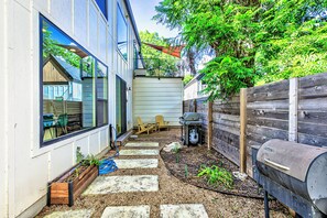 Un jardin avec un barbecue, une terrasse en bois et un parterre de fleurs.