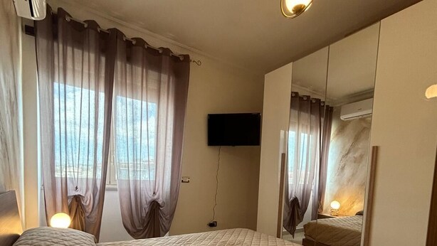 Hotellihuone, jossa on suuri sänky, seinälle asennettu taulutelevisio ja ilmastointilaite.