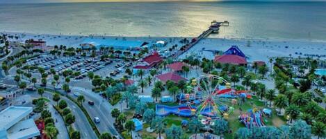A coastal amusement park with a Ferris wheel, roller coaster, and various rides.