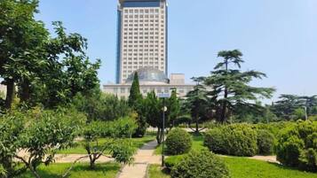Un hotel con un edificio alto, rodeado de un jardín bien cuidado con varios árboles y arbustos.