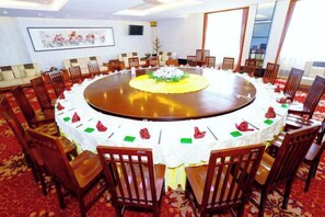 Une salle de conférence avec une table ronde, des chaises et un sol recouvert de moquette.