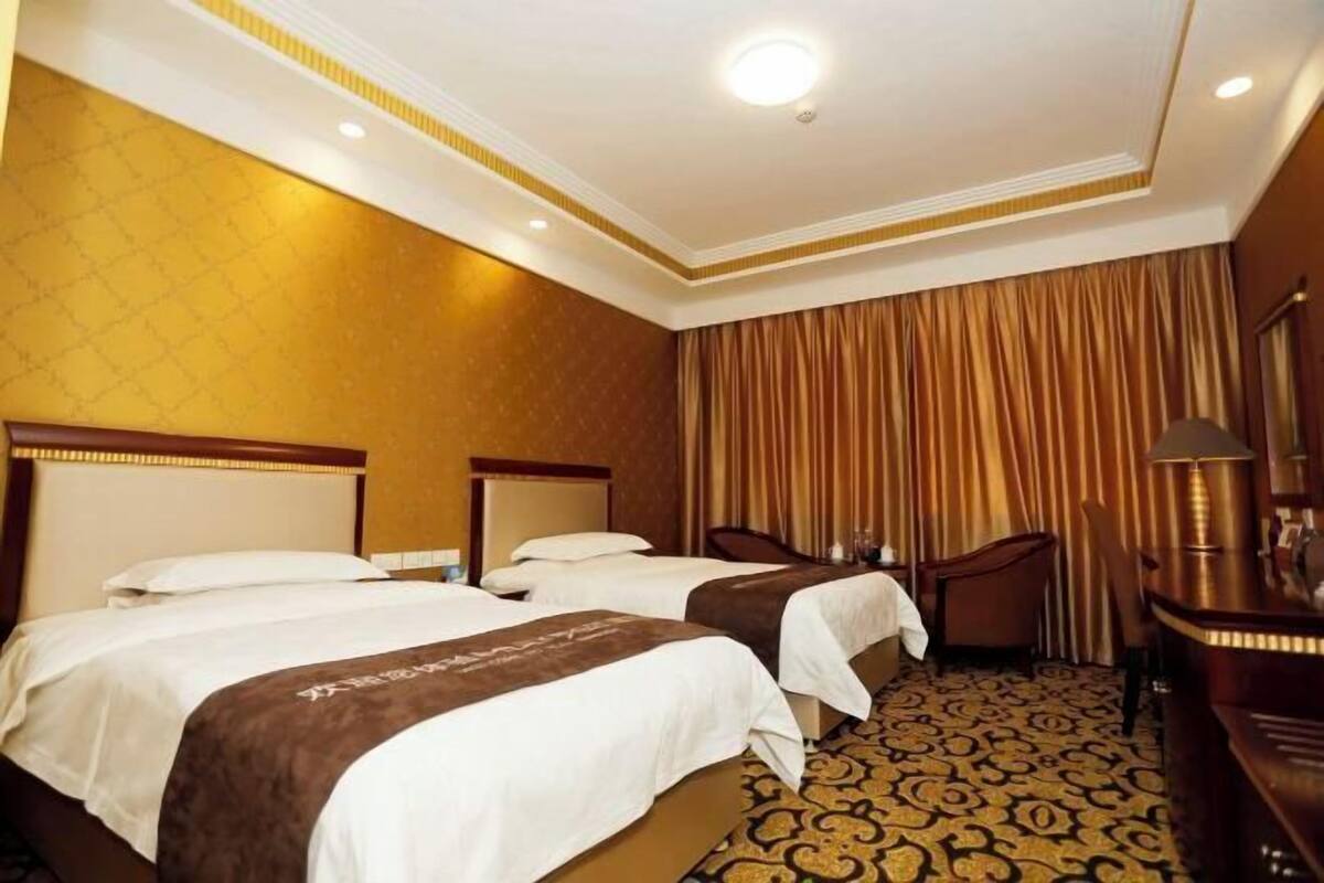 A hotel room with two beds, a desk, and a chair.